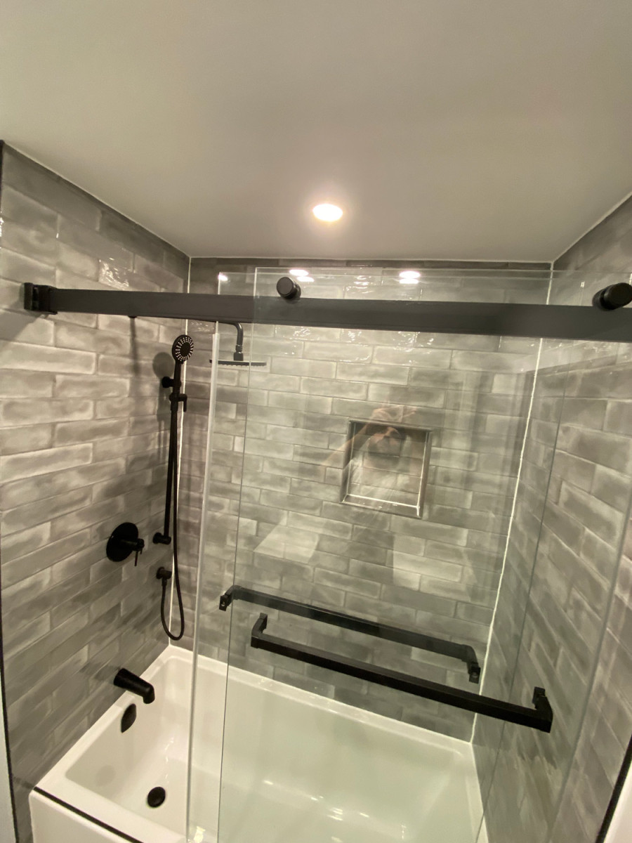 A bathroom with a walk-in shower featuring sleek custom glass doors.