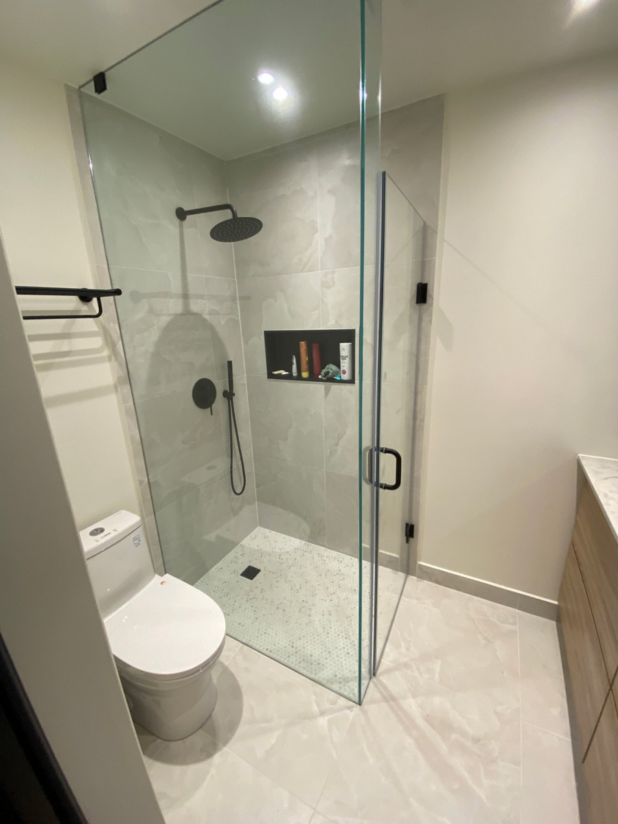 Bathroom with a walk-in shower featuring custom glass doors